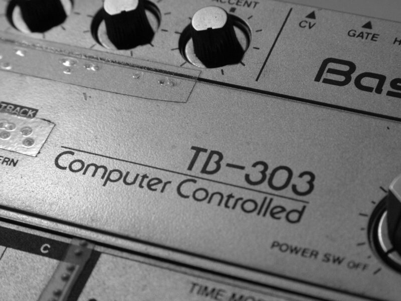 Close-p of vintage TB-303 hardware showing "Computer-Controlled" logo and knobs. "Old Roland TB-303" by Alexandre Dulaunoy is licensed under CC BY-SA 2.0.