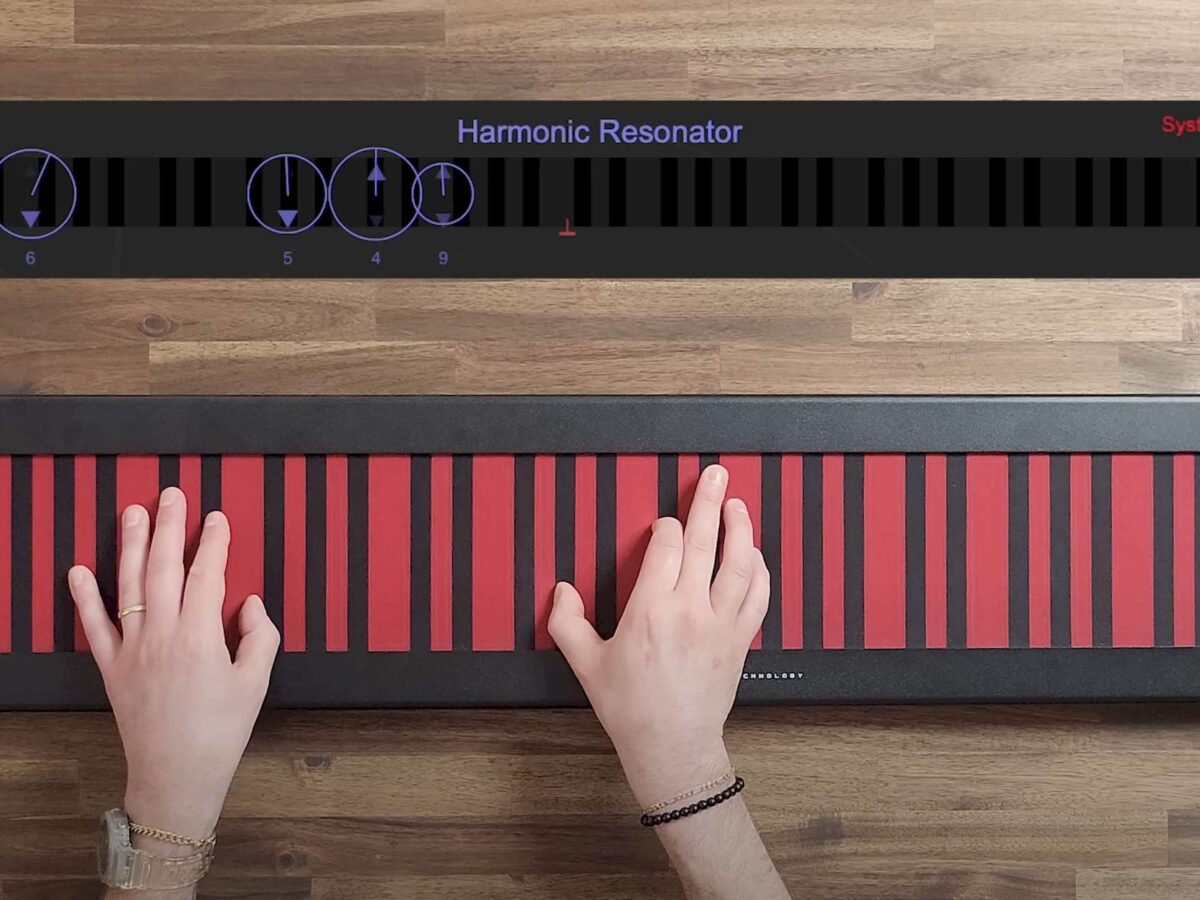 Still from Haken Continuum video with hands on the red-and-black horizontal ribbon controller of the Continuum Fingerboard; visualization above with Harmonic Resonator, circles overlaid on keyboard showing multi-dimensional expression.