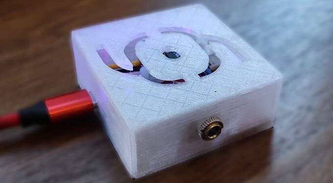 Therminator, with a curvy abstract glyph of a box with cables and a dot in the center engraved into the 3D-printed case, USB-C and jack connections